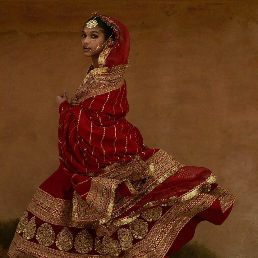 Featuring an embroidered red bridal lehenga with an embroidered organza  dupatta. Paired with jewellery from Sabyasachi